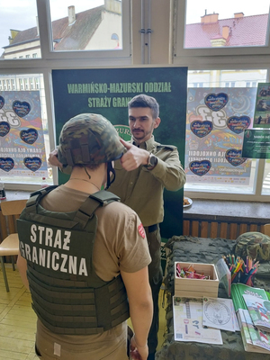Funkcjonariusz z W-MOSG pokazuje wyposażenie funkcjonariusza SG Funkcjonariusz z W-MOSG pokazuje wyposażenie funkcjonariusza SG